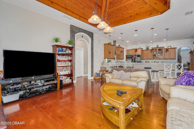 living room with hardwood / wood-style floors, wood ceiling, and brick wall