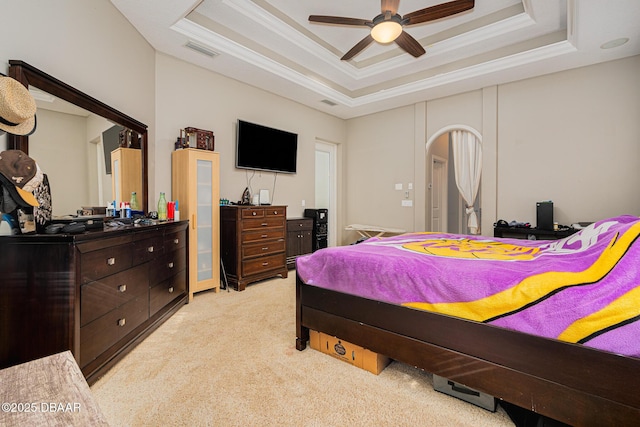 bedroom with light carpet, a tray ceiling, and ceiling fan