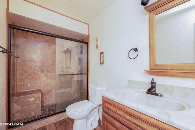 bathroom featuring wood-type flooring, toilet, a textured ceiling, vanity, and walk in shower