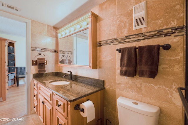 bathroom with wood-type flooring, vanity, toilet, and tile walls