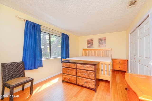 bedroom with a closet, hardwood / wood-style floors, and a textured ceiling