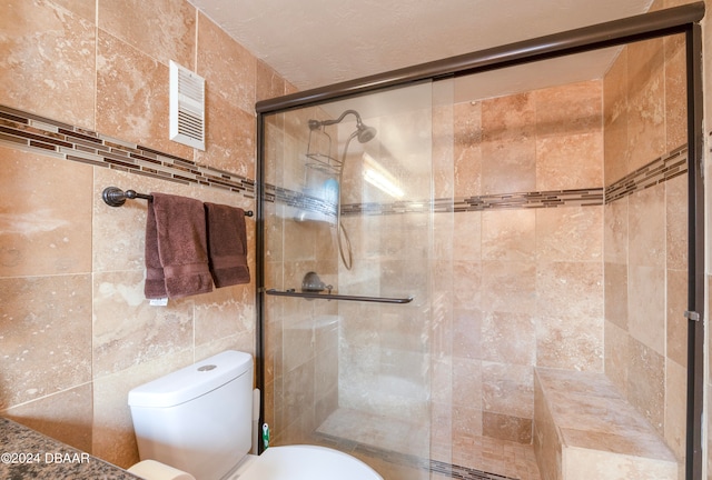 bathroom with a shower with door, toilet, and tile walls