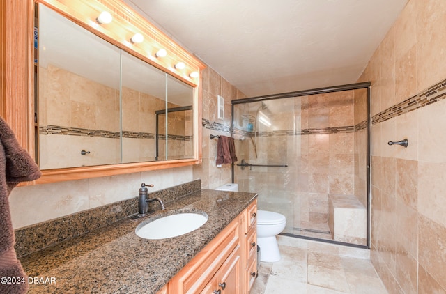 bathroom with tile walls, an enclosed shower, vanity, and toilet