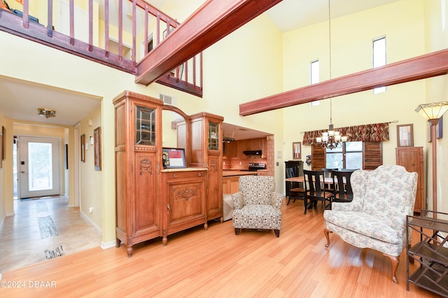 living area featuring a high ceiling, light wood-type flooring, a wealth of natural light, and a notable chandelier