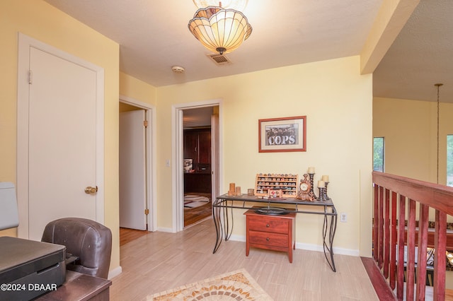 hall with a textured ceiling and light hardwood / wood-style flooring