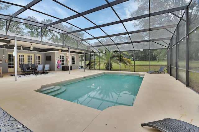 view of swimming pool with glass enclosure, ceiling fan, and a patio area