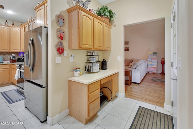 kitchen featuring light tile patterned floors, light brown cabinetry, backsplash, and appliances with stainless steel finishes