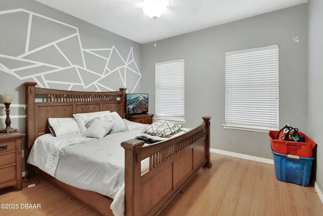 bedroom with multiple windows and light hardwood / wood-style flooring