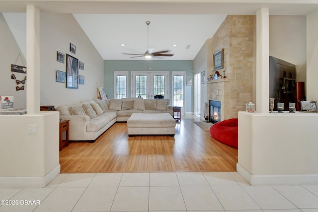 tiled living room with a tiled fireplace, ceiling fan, and vaulted ceiling