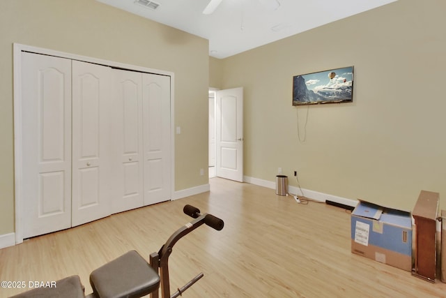 exercise room with ceiling fan and light hardwood / wood-style floors