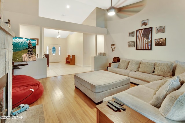 living room featuring ceiling fan, light hardwood / wood-style floors, and lofted ceiling