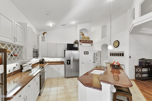 kitchen featuring sink, appliances with stainless steel finishes, a kitchen bar, white cabinets, and a kitchen island