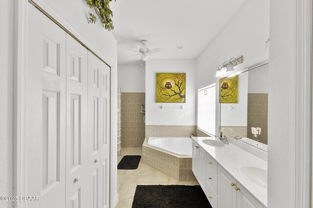 bathroom featuring a relaxing tiled tub, vanity, tile patterned floors, and ceiling fan