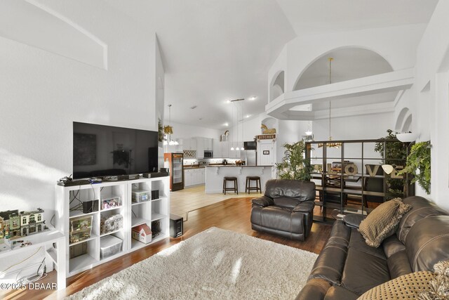 living room with high vaulted ceiling, a notable chandelier, and light hardwood / wood-style floors