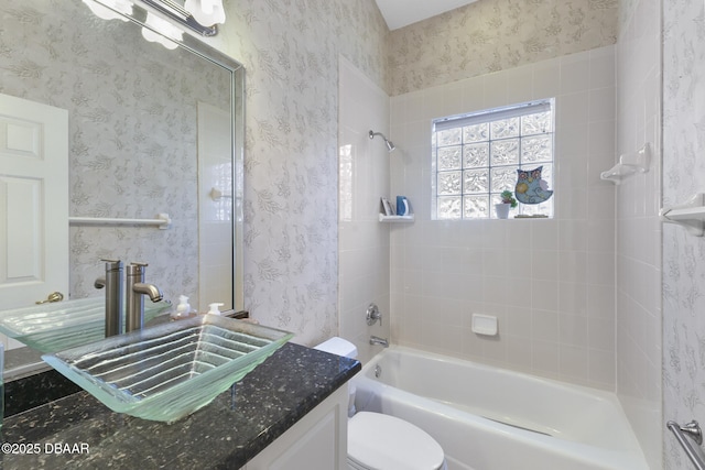 full bathroom with tiled shower / bath, vanity, and toilet