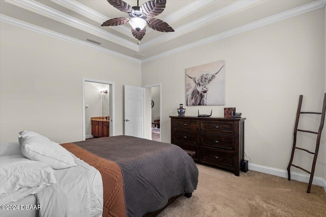 carpeted bedroom featuring a tray ceiling, crown molding, ceiling fan, and ensuite bath