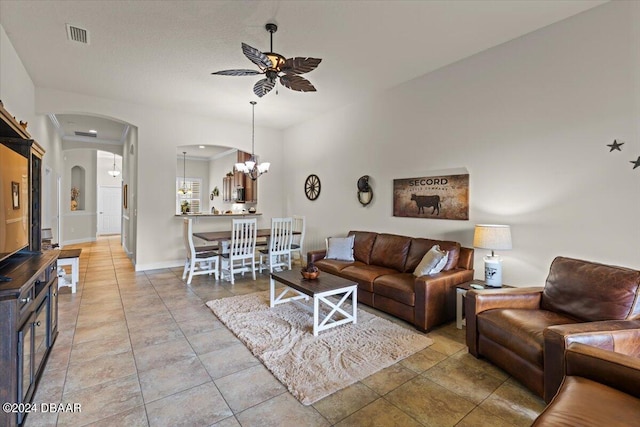 tiled living room with ceiling fan with notable chandelier