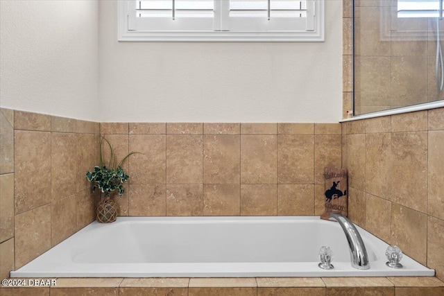 bathroom featuring a wealth of natural light and tiled bath