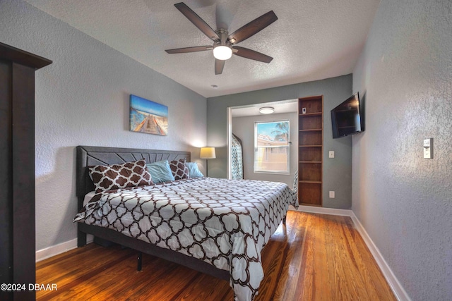 bedroom with ceiling fan, wood-type flooring, and a textured ceiling