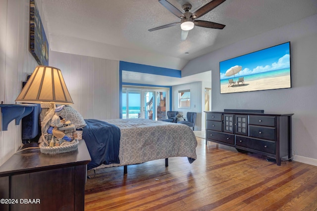 bedroom featuring hardwood / wood-style flooring, vaulted ceiling, ceiling fan, and a textured ceiling