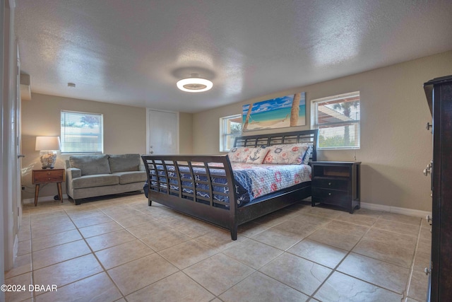 bedroom featuring multiple windows, tile patterned flooring, and a textured ceiling