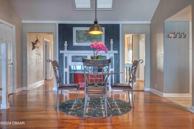 dining space featuring wood-type flooring and vaulted ceiling