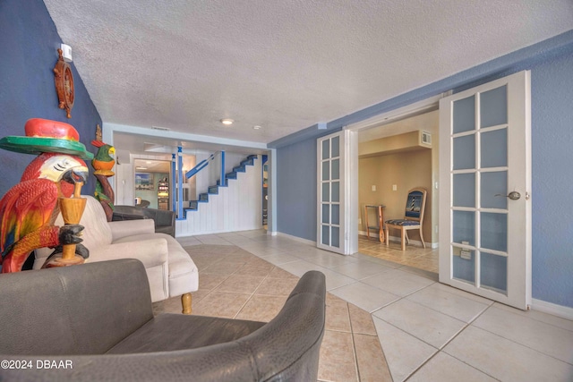 living room with tile patterned flooring, french doors, and a textured ceiling