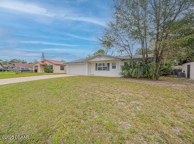 ranch-style house featuring driveway, an attached garage, central AC unit, and a front lawn