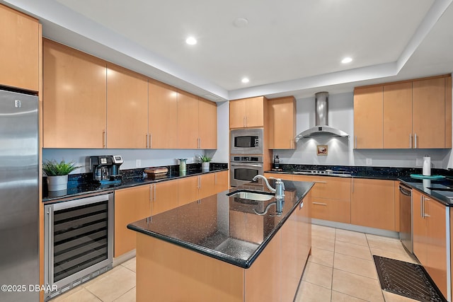 kitchen with sink, wall chimney range hood, wine cooler, a center island with sink, and appliances with stainless steel finishes