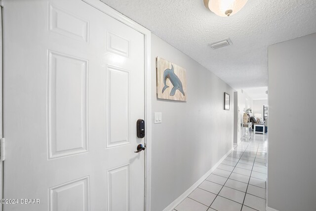 hall with light tile patterned flooring and a textured ceiling