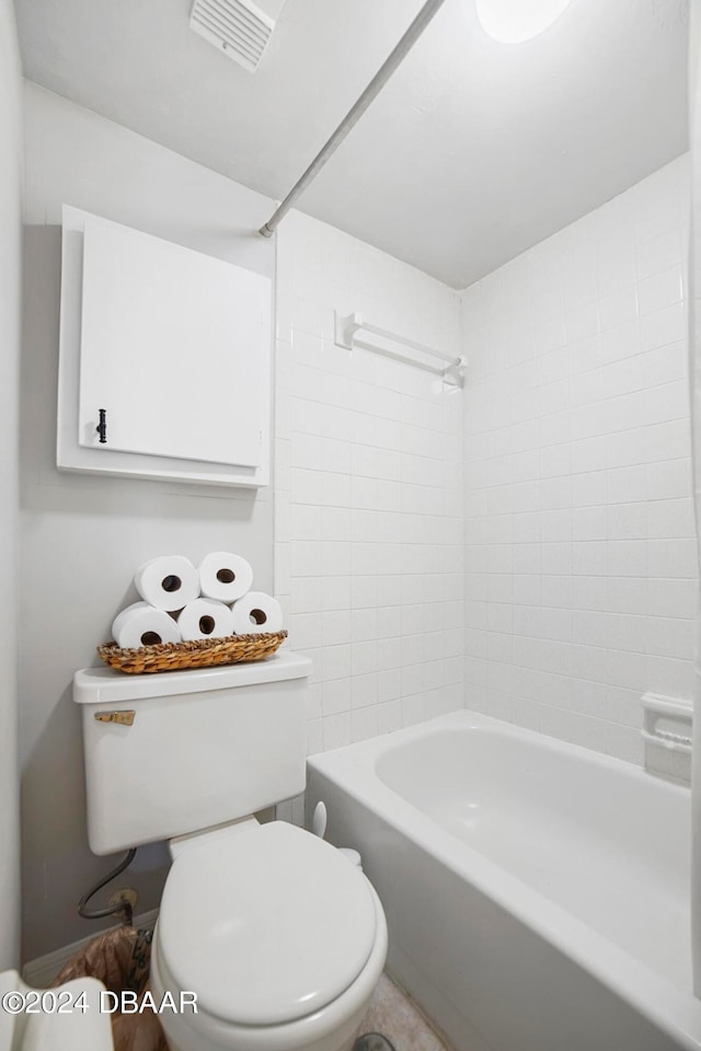 bathroom with tiled shower / bath combo and toilet