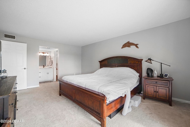 bedroom with ensuite bath and light carpet