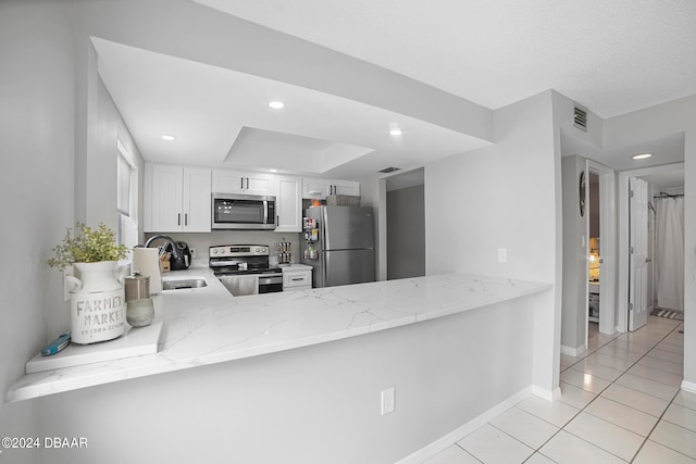 kitchen with stainless steel appliances, sink, light stone counters, kitchen peninsula, and white cabinets