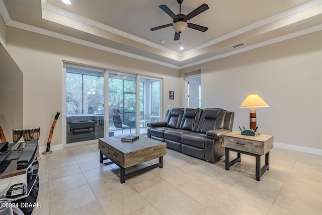 living room with light tile patterned flooring, ceiling fan, a raised ceiling, and crown molding