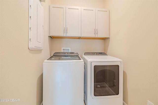 clothes washing area with electric panel, cabinets, and independent washer and dryer