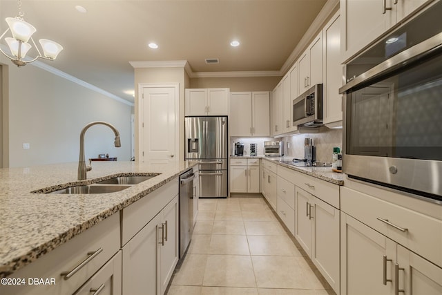 kitchen with pendant lighting, sink, light stone counters, and stainless steel appliances