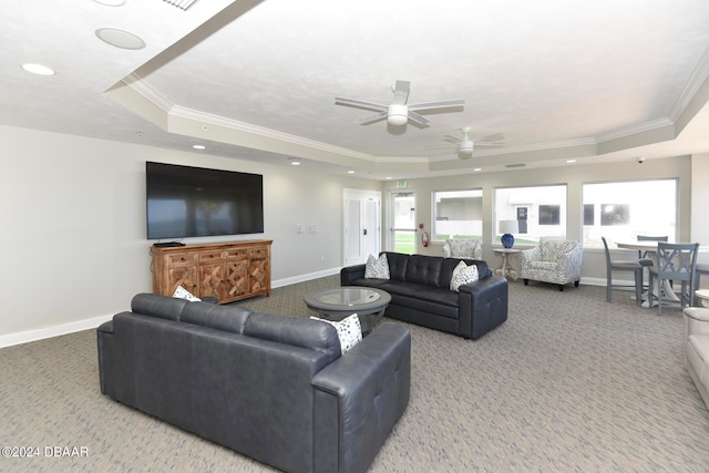 carpeted living room with ornamental molding, ceiling fan, plenty of natural light, and a tray ceiling