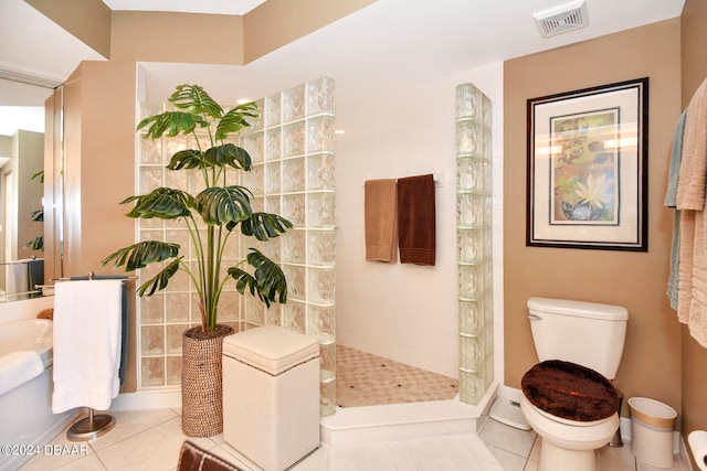 bathroom with tile patterned flooring, toilet, and a tile shower