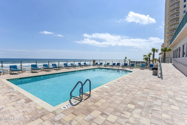 view of swimming pool featuring a water view and a patio area