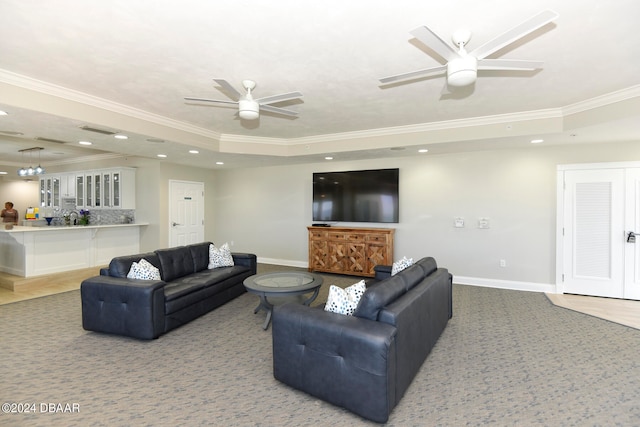 living room with ornamental molding, ceiling fan, and a raised ceiling