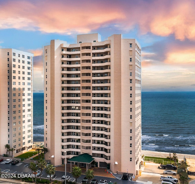 outdoor building at dusk featuring a beach view and a water view