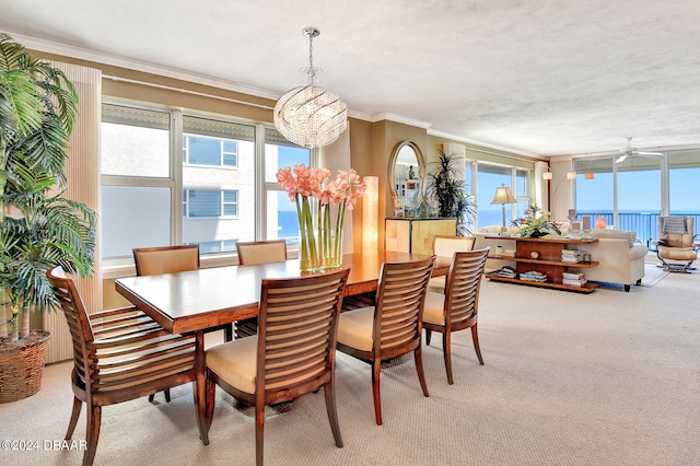 dining room with a water view, light carpet, ornamental molding, and ceiling fan with notable chandelier