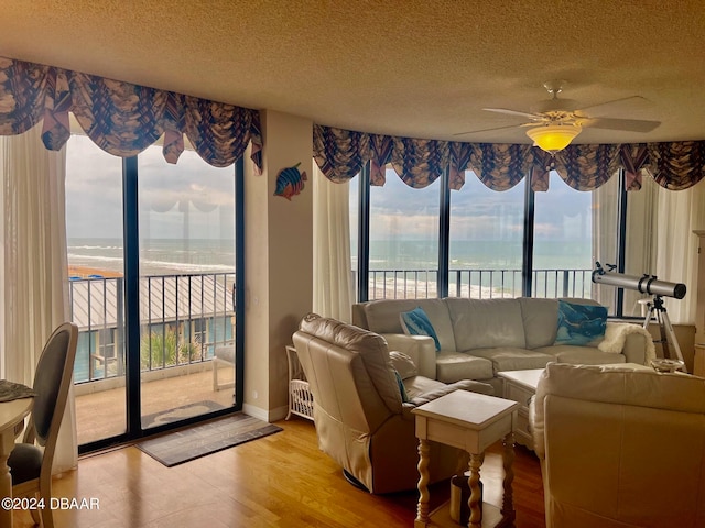 living room with a wealth of natural light, light wood-type flooring, a water view, and ceiling fan