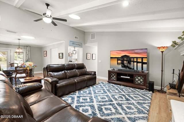 living area with visible vents, vaulted ceiling with beams, a ceiling fan, light wood-type flooring, and baseboards