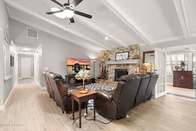 living area with visible vents, lofted ceiling with beams, a fireplace, light wood-style flooring, and ceiling fan