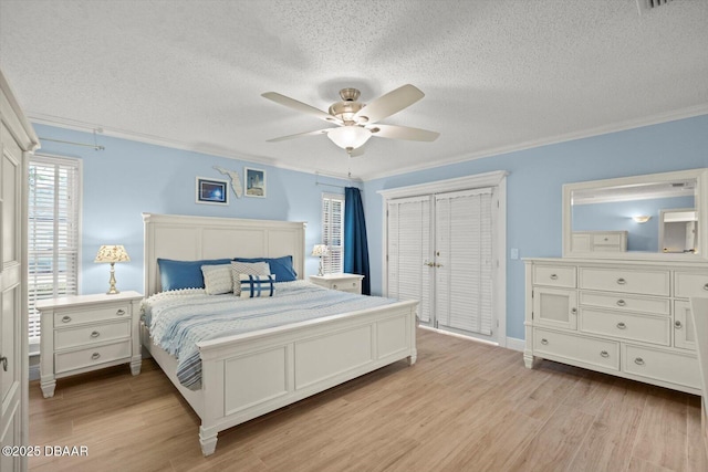 bedroom with light wood-style flooring, a textured ceiling, ornamental molding, and a ceiling fan