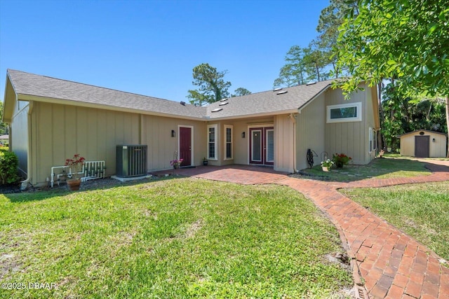 rear view of property featuring a storage unit, cooling unit, a patio area, an outdoor structure, and a yard
