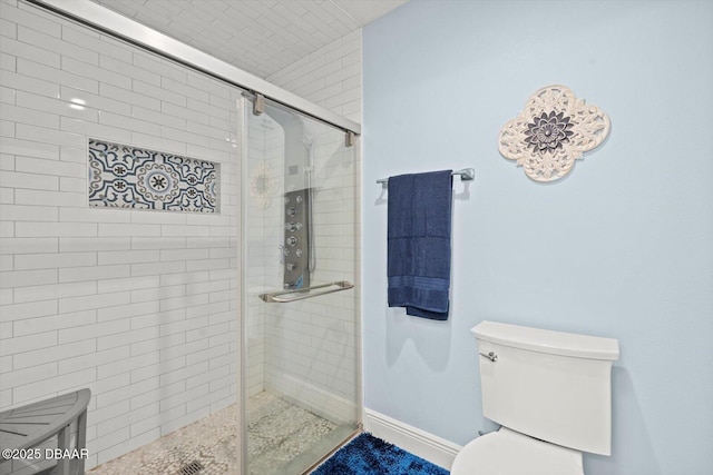 bathroom with toilet, baseboards, and a stall shower