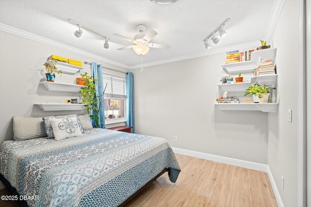 bedroom featuring a textured ceiling, wood finished floors, rail lighting, and crown molding
