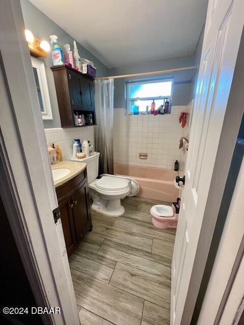 full bathroom with toilet, shower / tub combo, vanity, and tasteful backsplash